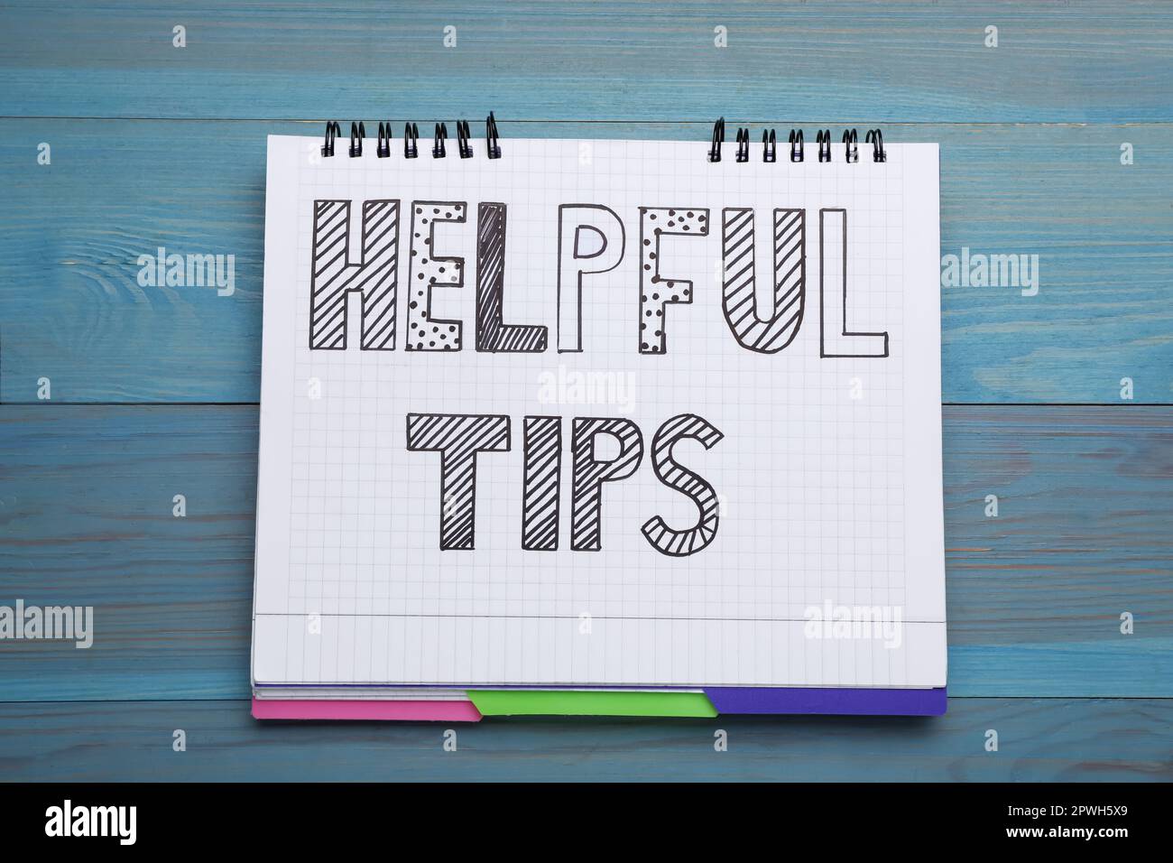 Phrase Helpful Tips in notebook on light blue wooden table, top view Stock Photo