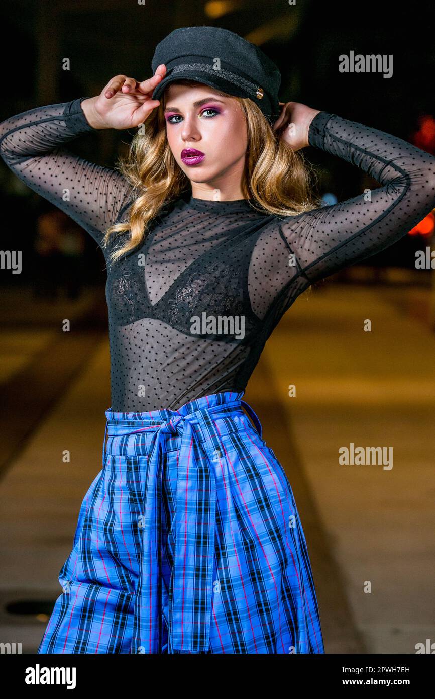 A young girl in stylish clothes poses on the street of a night city