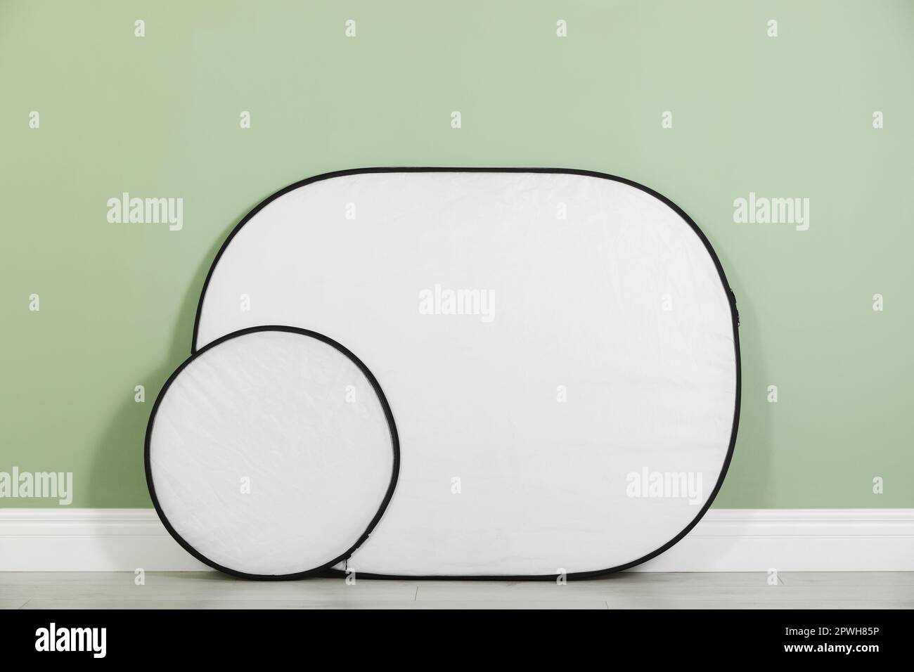 Studio reflectors near pale green wall in room. Professional