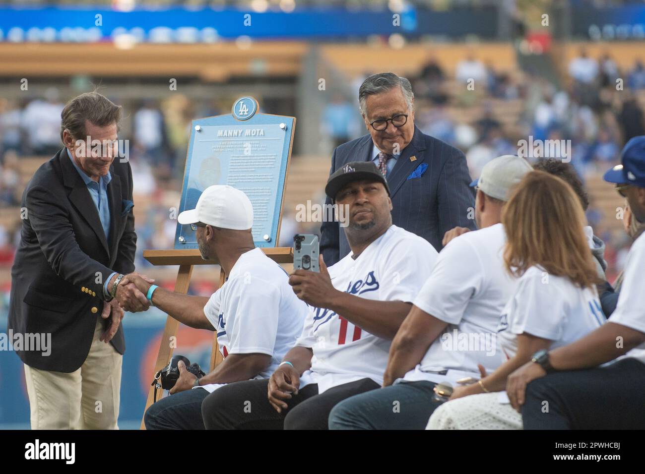 Former Los Angeles Dodger Manny Mota, right, speaks as his son Jose looks  on as he is inducted into the Legends of Dodger Baseball prior a baseball  game between the Dodgers and