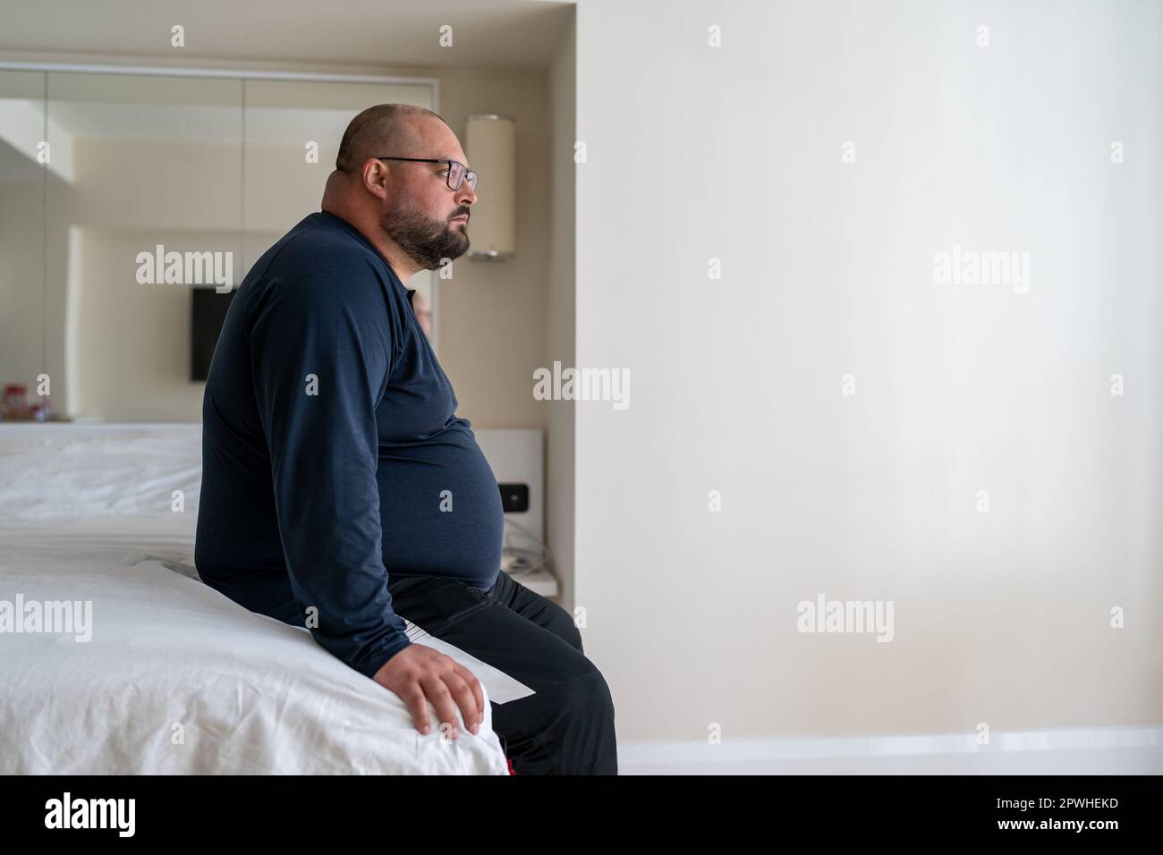 Calm sleepy man waking up in morning at home sitting in bed ready 