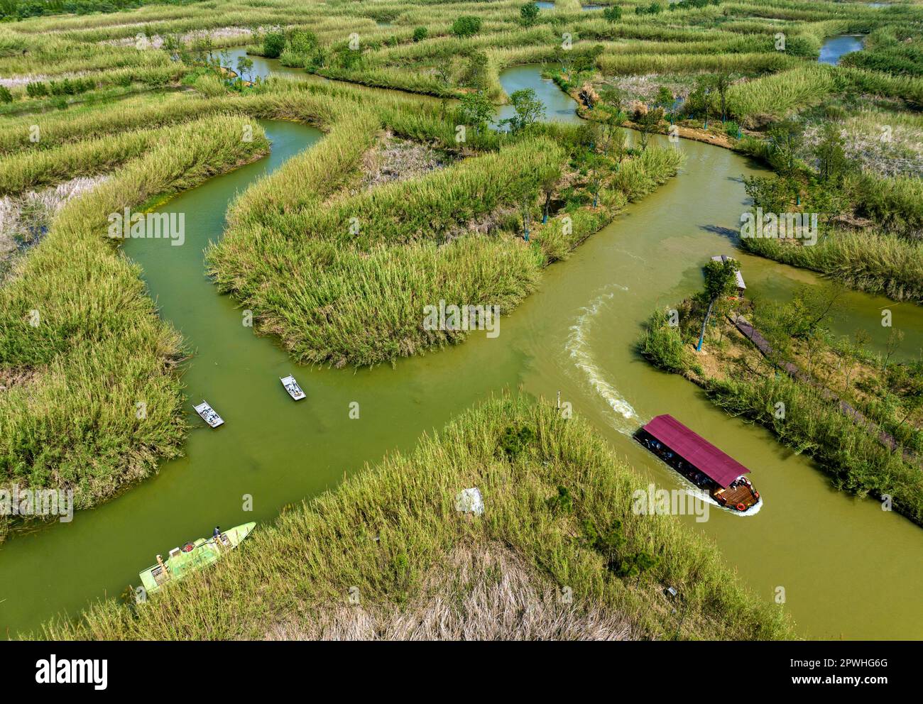 SUQIAN, CHINA - APRIL 30, 2023 - Aerial photo taken on April 30, 2023 shows tourists riding bamboo rafts and boats to play at Hongze Lake Wetland in S Stock Photo