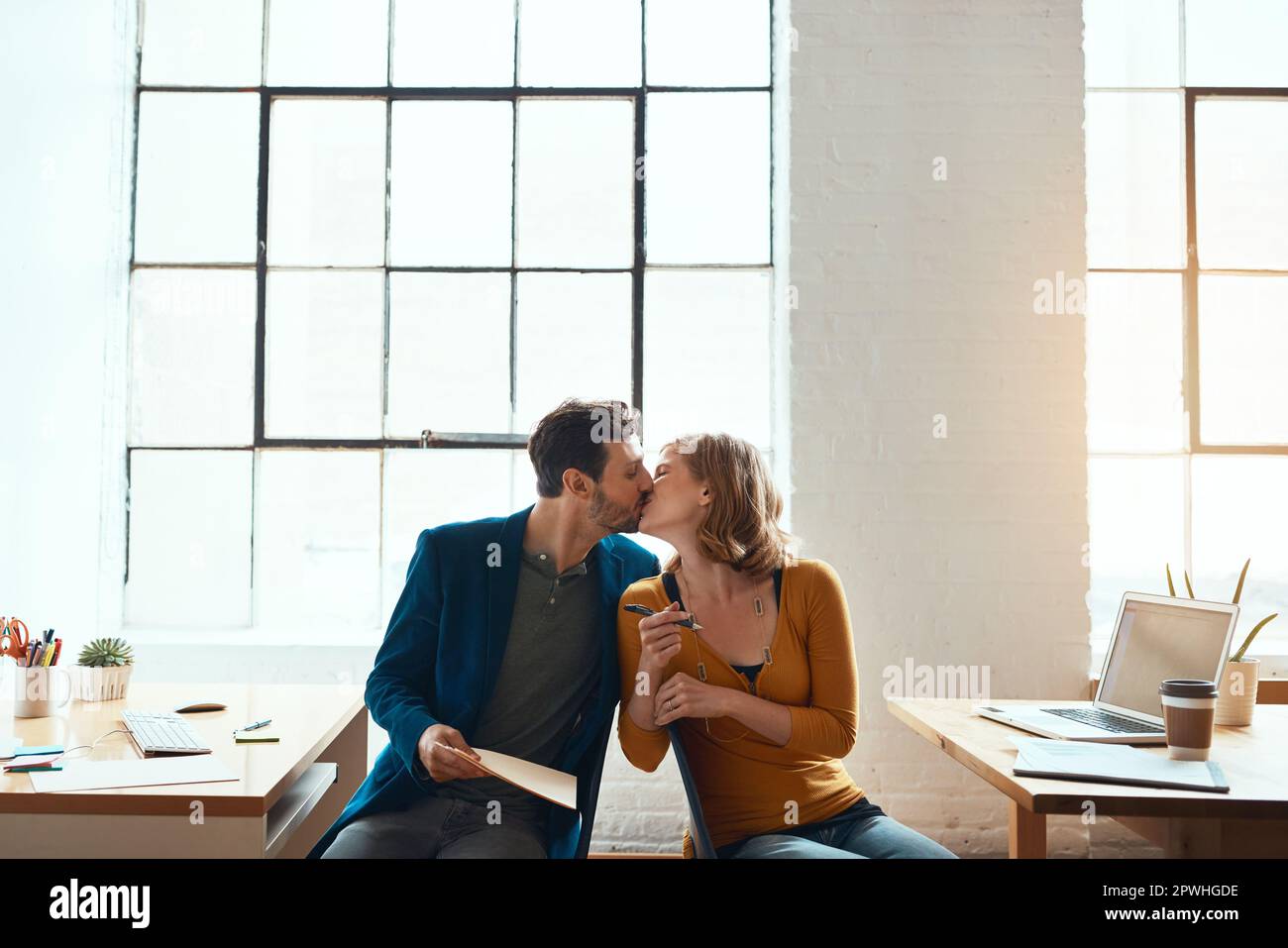Theyre lucky they work together. young couple kissing while working