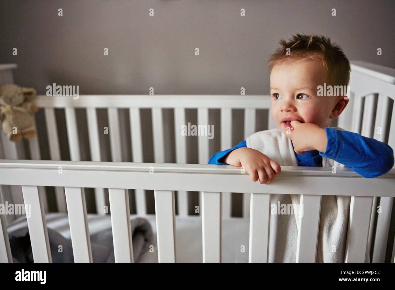 sun-is-up-and-so-am-i-a-cute-little-baby-boy-standing-in-his-cot-stock