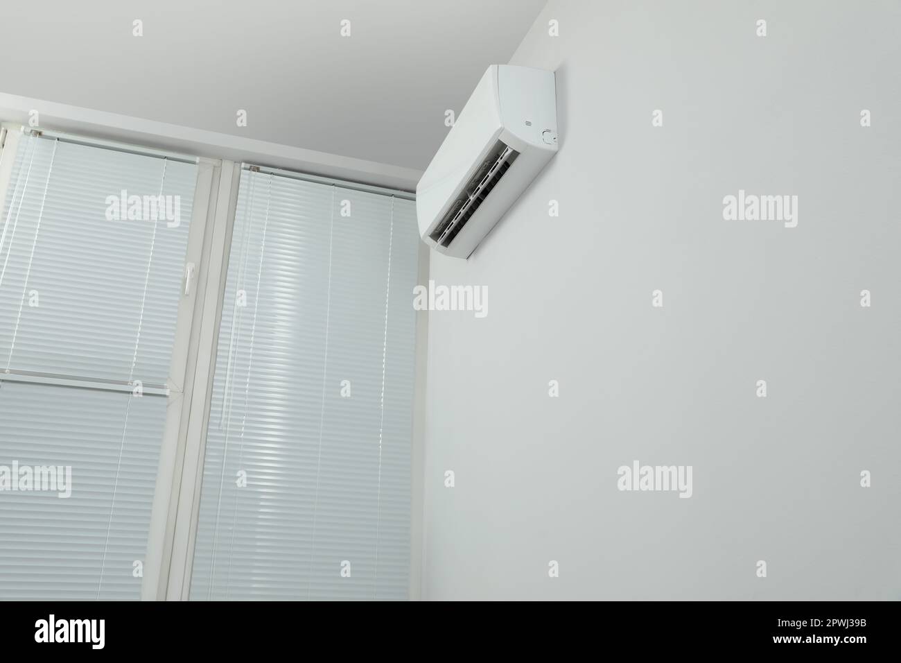 Modern air conditioner on white wall indoors, low angle view. Space for ...