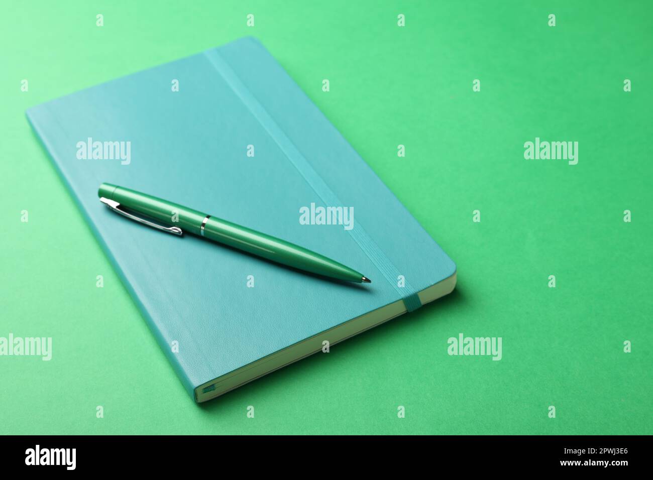 New stylish planner with hard cover and pen on green background Stock Photo