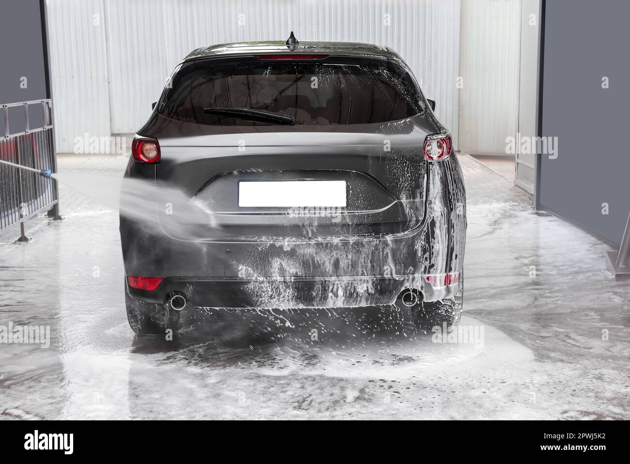 Washing auto with high pressure water jet at outdoor car wash Stock Photo