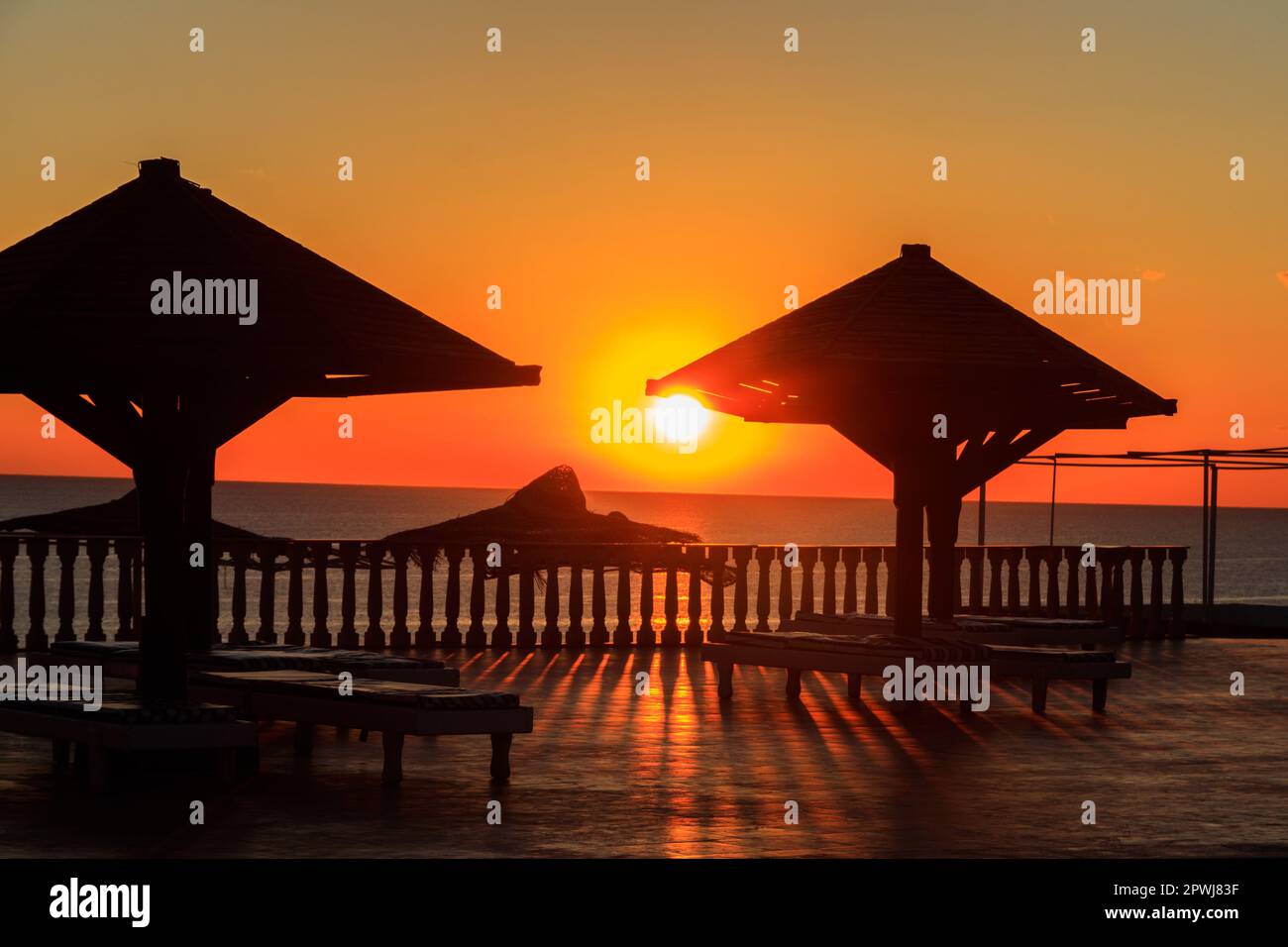 Sun umbrellas and chaise lounges on tropical beach at sunrise. Concept of rest, relaxation, holidays, resort Stock Photo