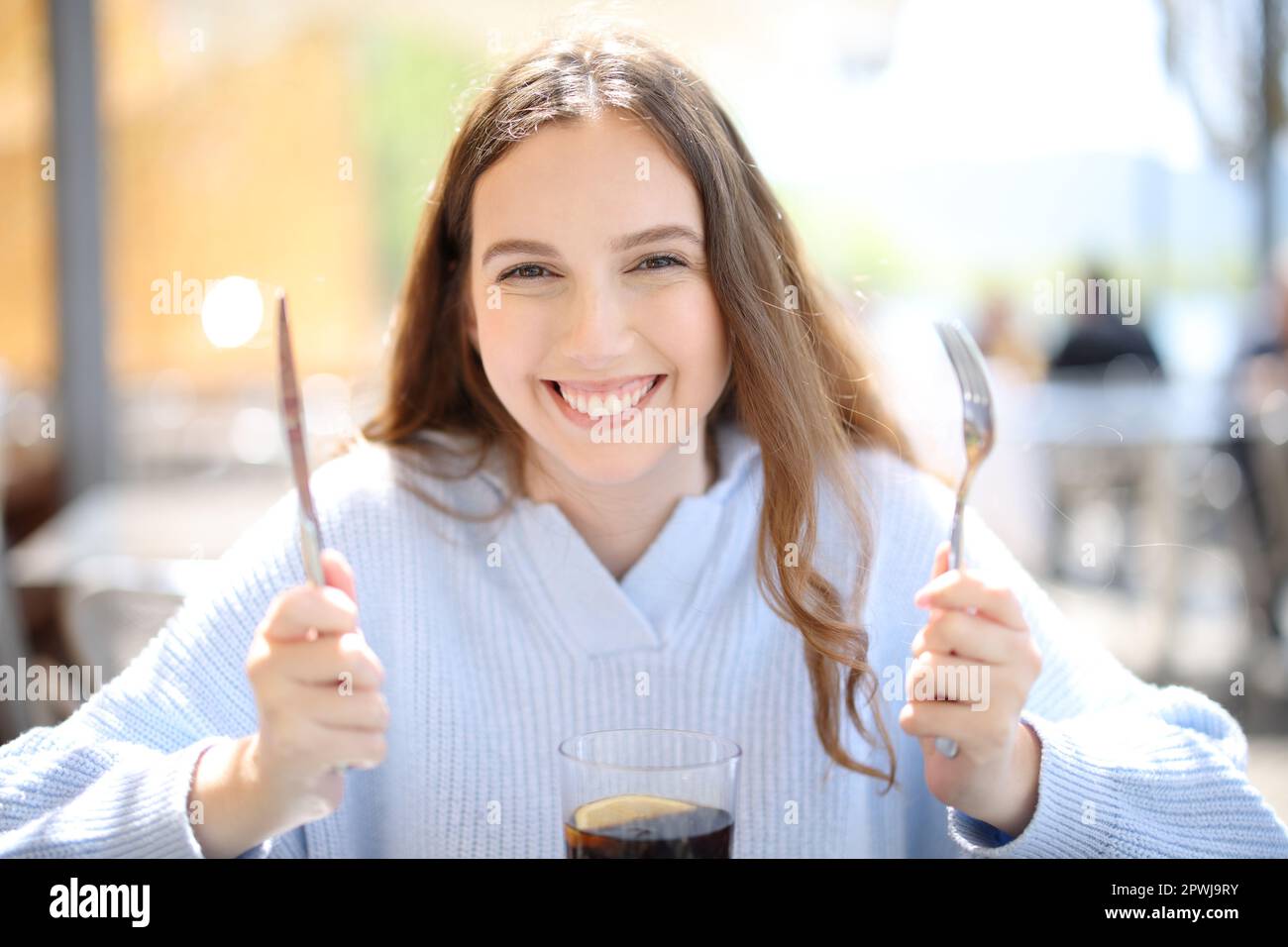 Front view of a happy restaurant customer ready to eat looking at camera Stock Photo