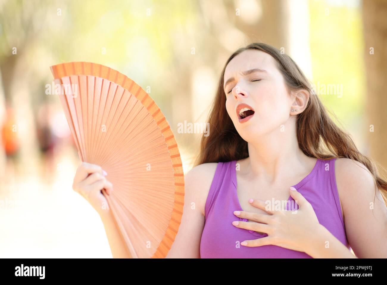 Woman stressing fanning on summer hot day in a park Stock Photo