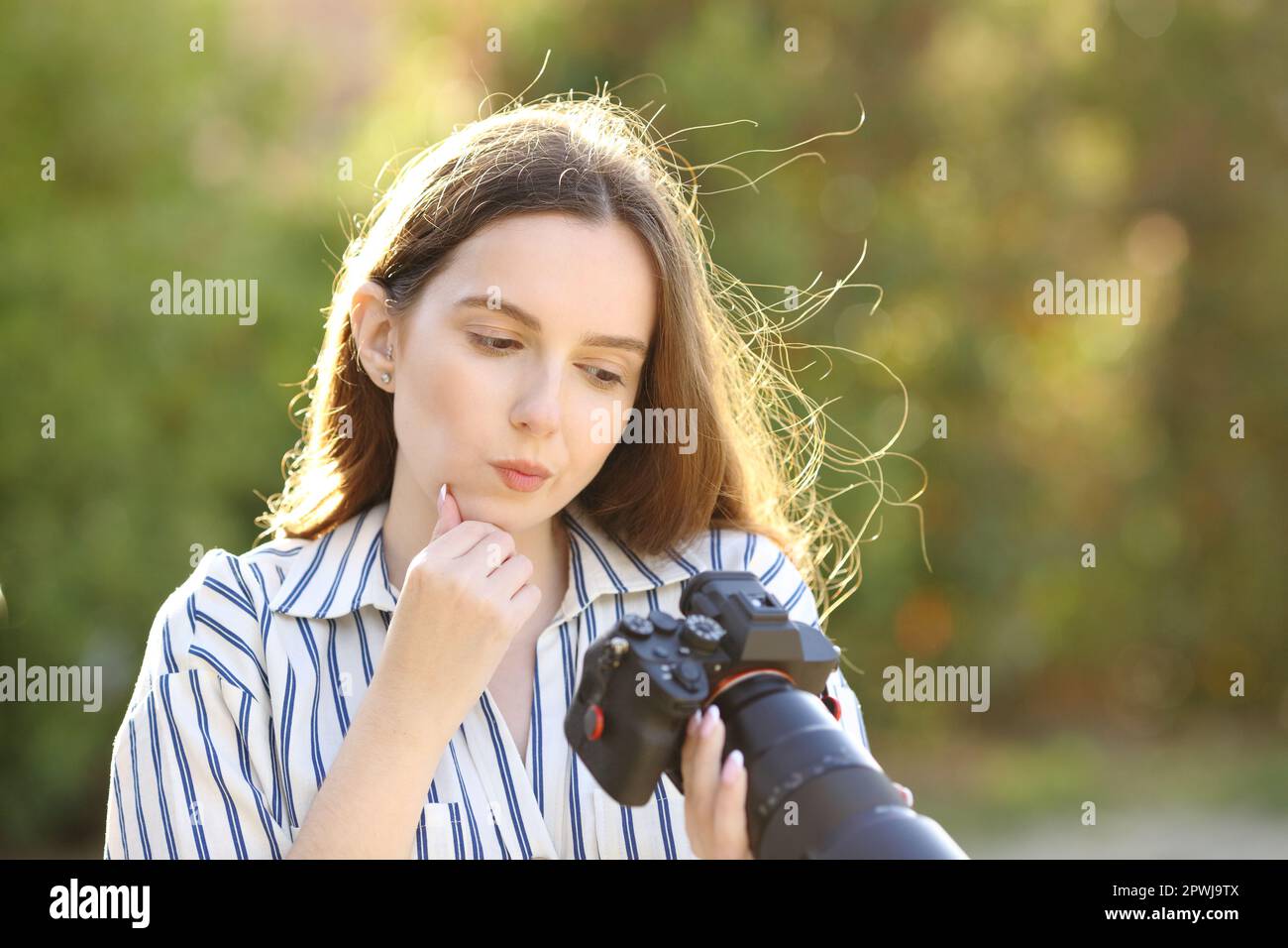 Doubtful photographer checking pictures on mirrorless camera in a park Stock Photo