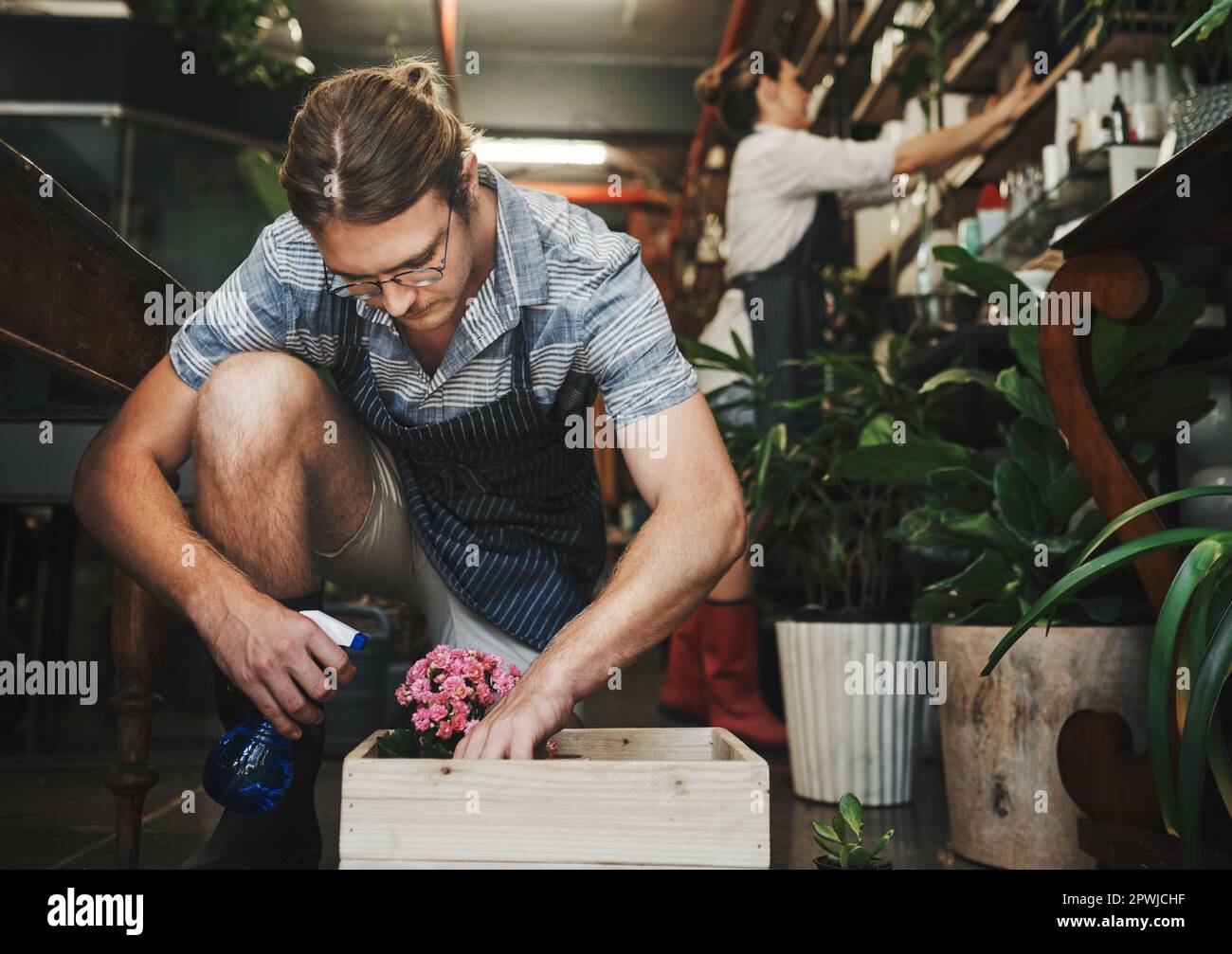 If you love your flowers, water them. a handsome young florist watering