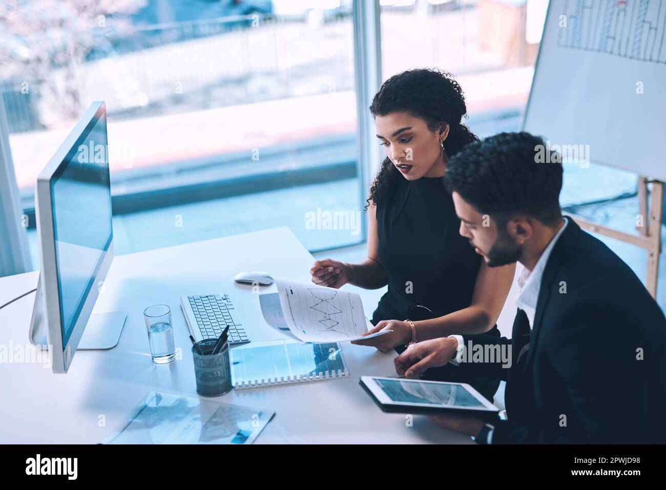 Just go through these please. two young businesspeople sitting together ...