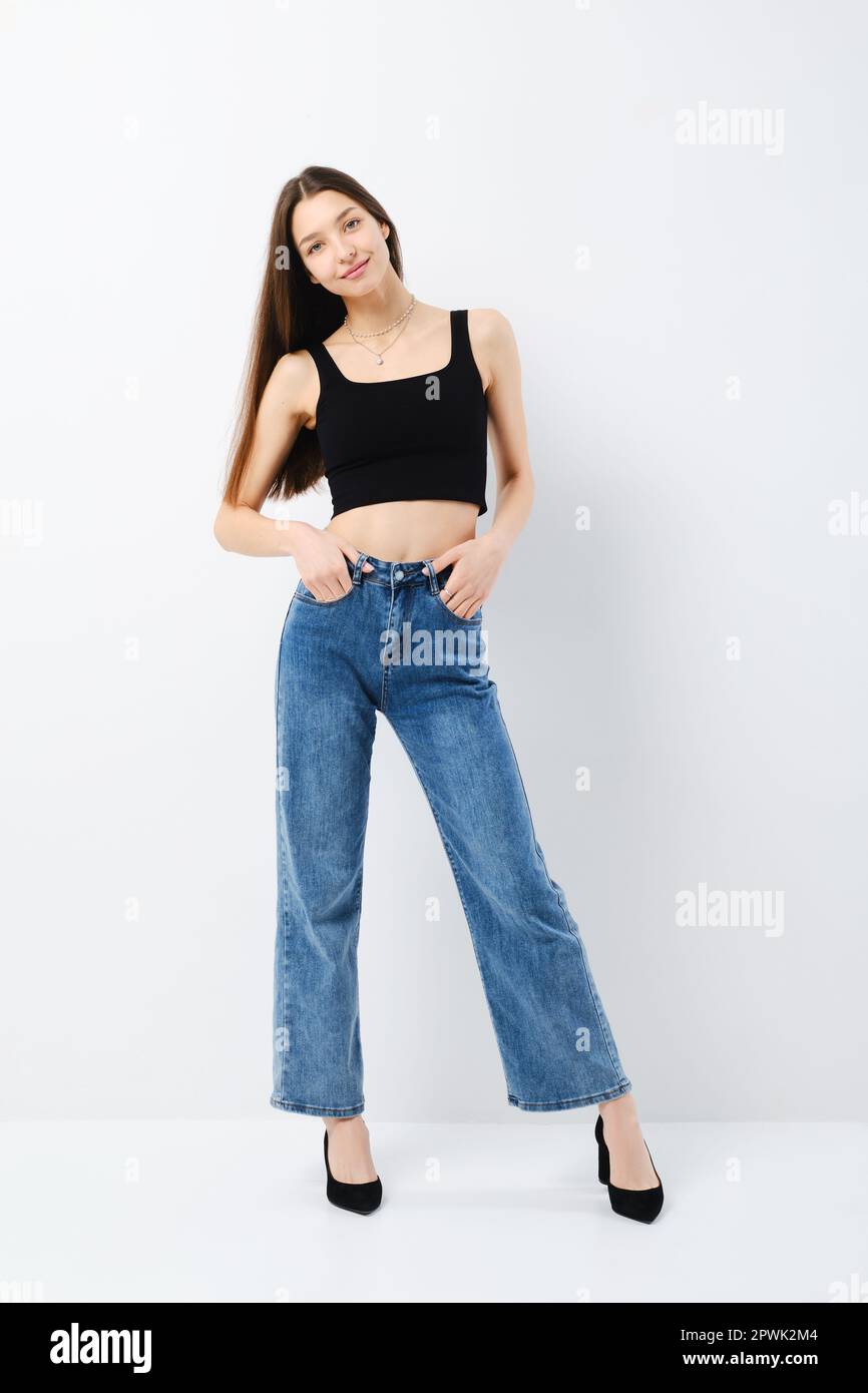 Full length portrait of smiling young woman in black tank top and wide ...