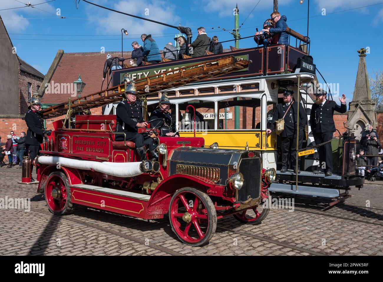 A vintage fire engine passes an equally vintage double decker tram car. Pictured at Beamish Living Museum, North East England. Stock Photo