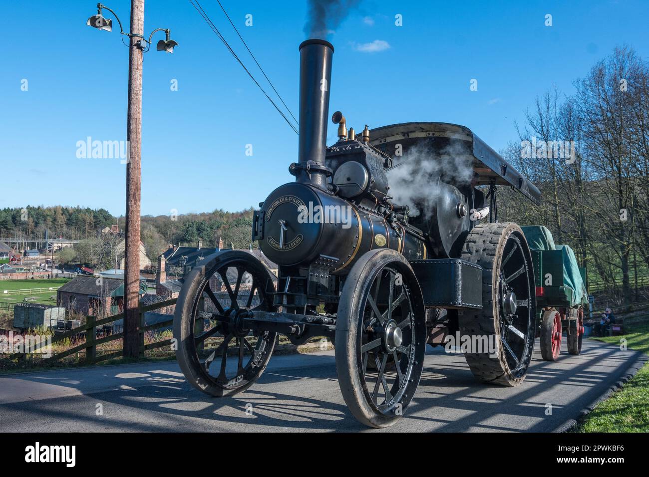 A steam traction engine works hard to pull a heavy trailer up a steep