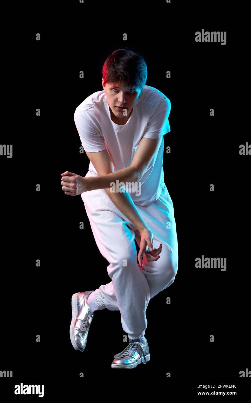 young man in white t-shirt dancing hip-hop in neon light on black ...