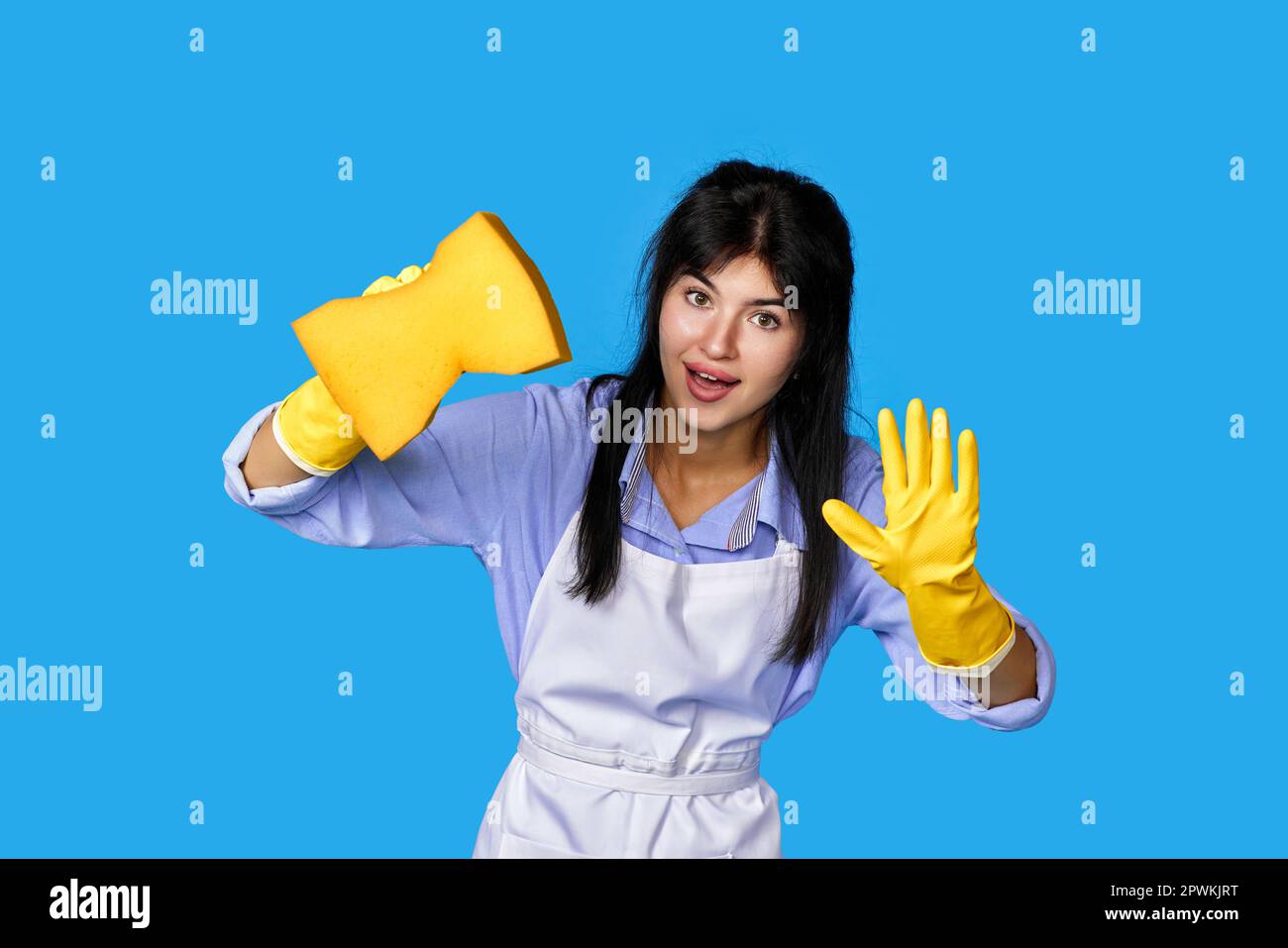 young confident woman in rubber gloves and cleaner apron cleaning with ...