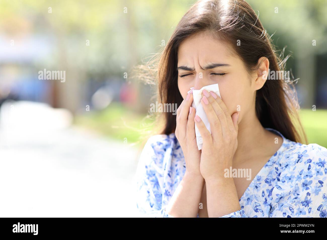 Ill woman blowing or coughing on tissue in the street Stock Photo
