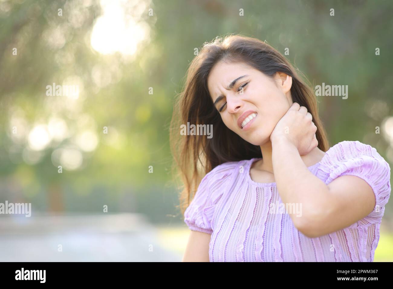 Stressed woman suffering neck ache alone in a park Stock Photo