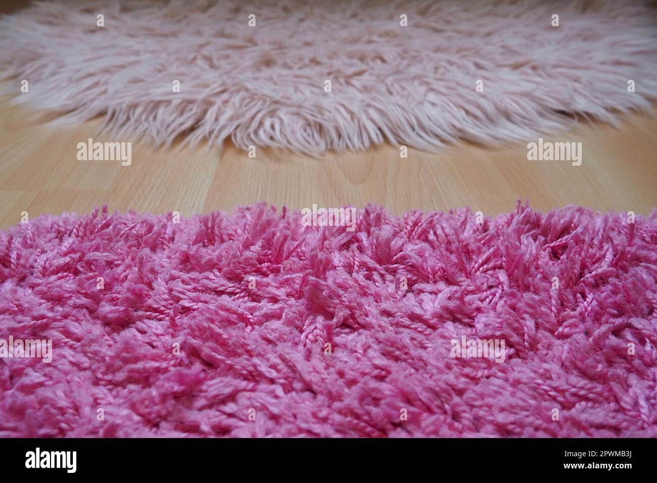 Long pile rug in pink on a beige laminate floor. Feminine interior for