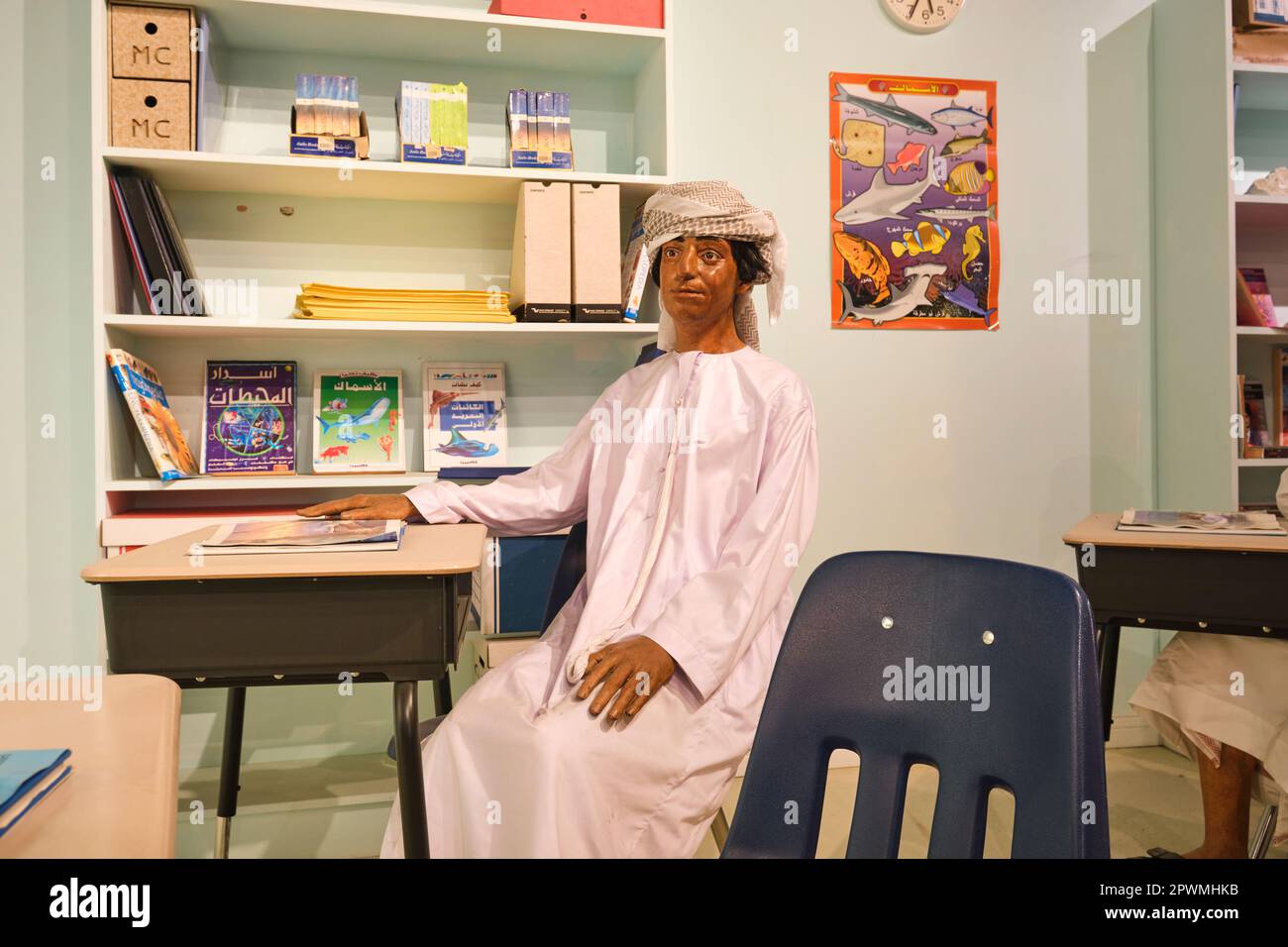 A boy, sitting at a desk in a school classroom, studying and learning, getting an education. A diorama depicting a scene from UAE's past, at the Abu D Stock Photo