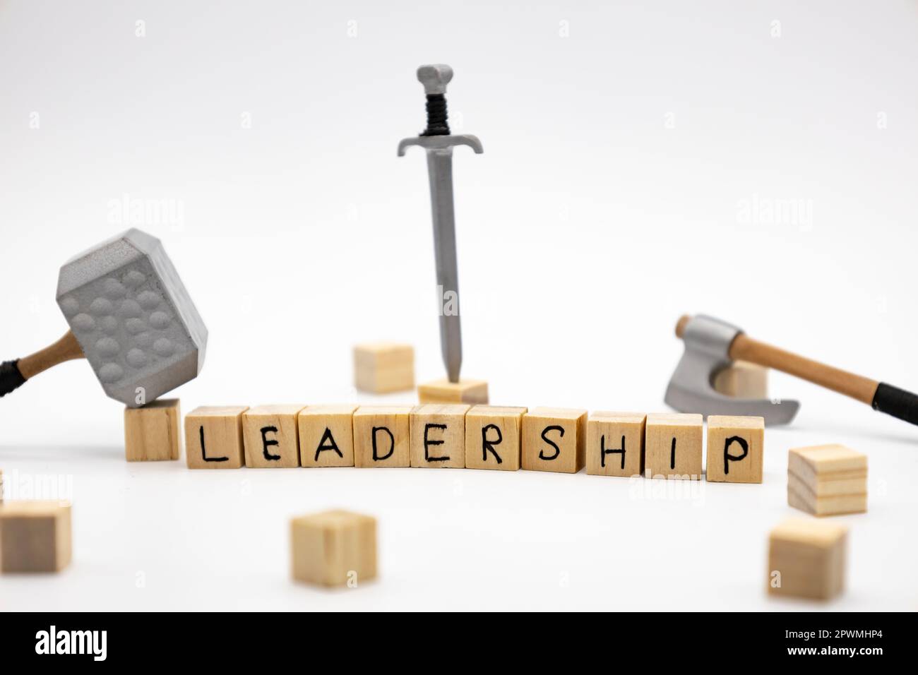 The wooden cubes with the word LEADERSHIP and the weapon around against white background. The medieval weapons is hammer, sword and axe. Stock Photo