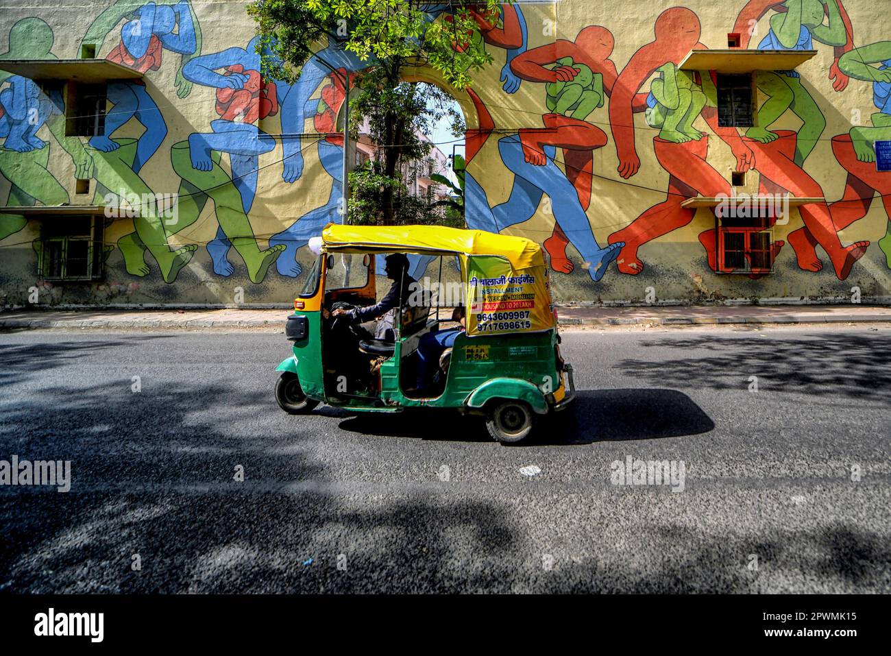 Delhi, India. 21st Apr, 2023. An auto rickshaw rides past a mural in