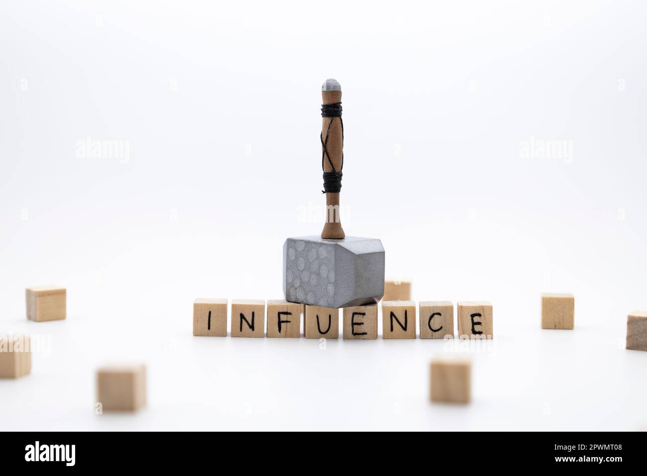 The hammer is standing on the wooden cubes with the word INFLUENCE against white background Stock Photo
