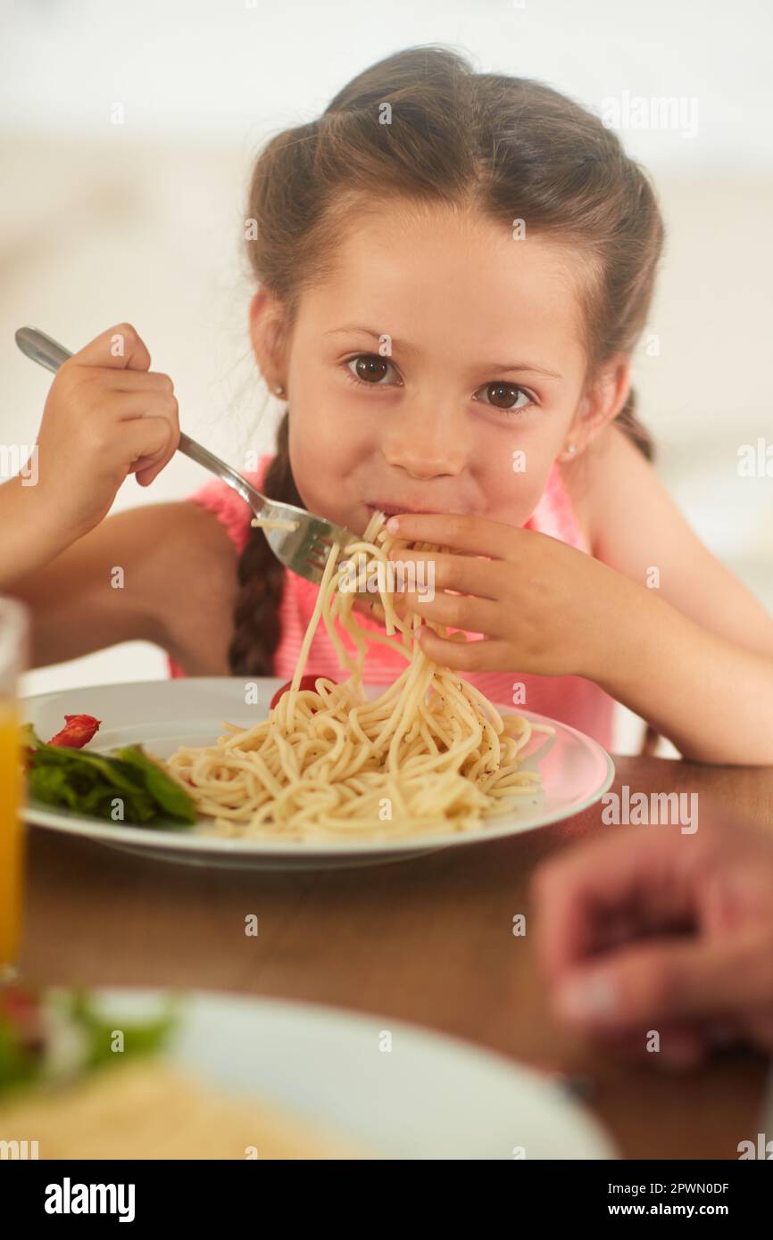 I asked mom to make my favorite. an adorable little girl eating her food at  home Stock Photo - Alamy