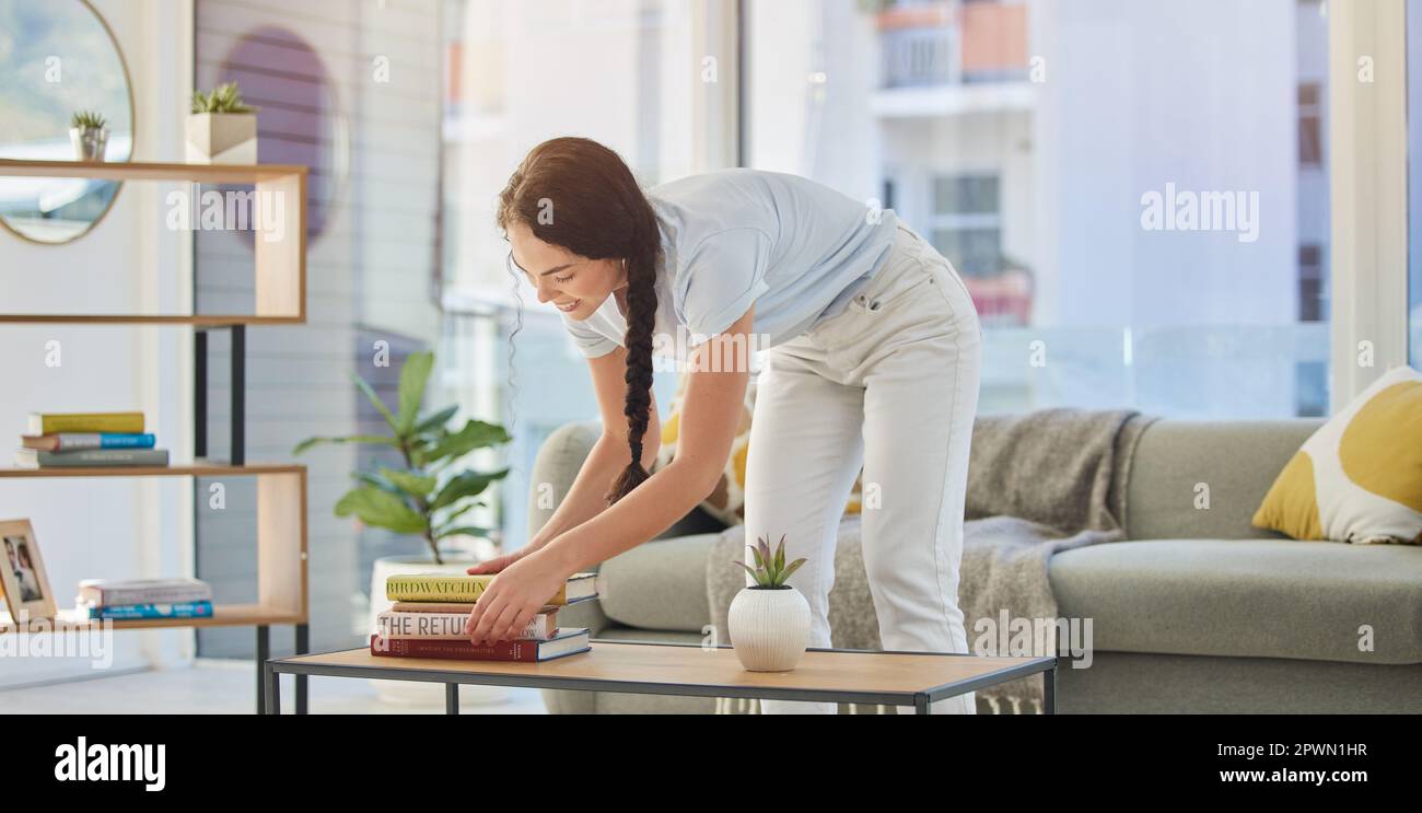 Woman, cleaning and house with books in lounge, table and organize for