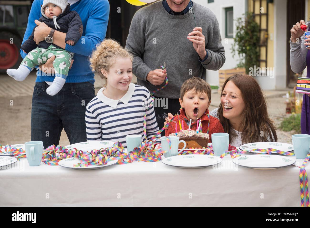 Little boy blowing out candles on his cake at his birthday party