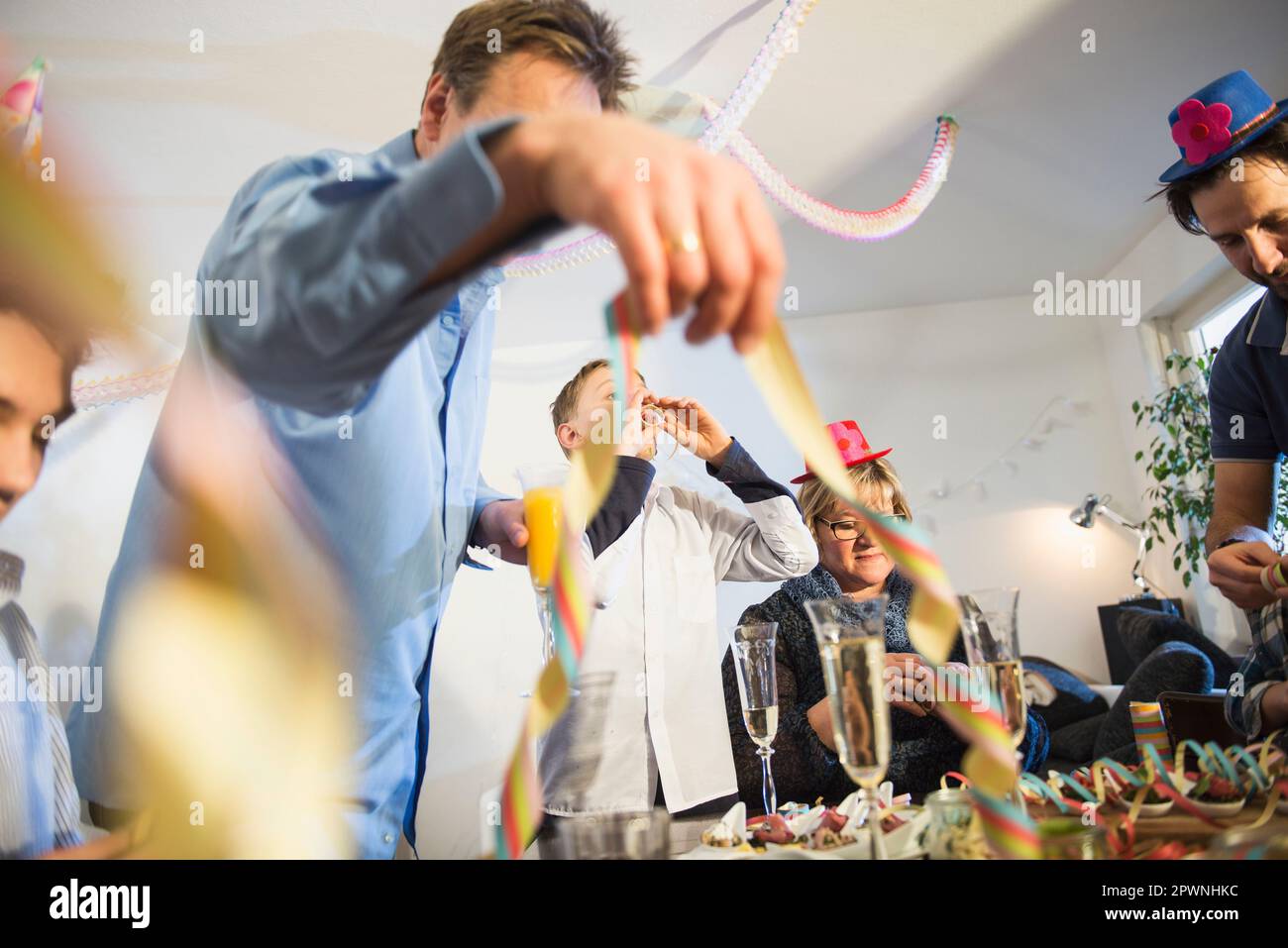 Guests blowing paper streamers at a party Stock Photo - Alamy