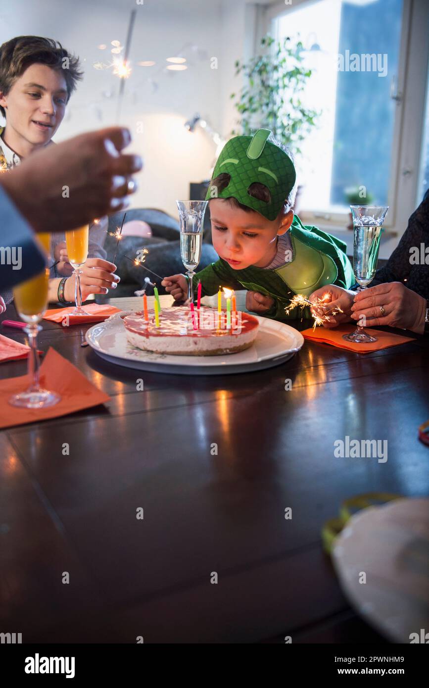 Little boy with costume blowing the candles on cake Stock Photo