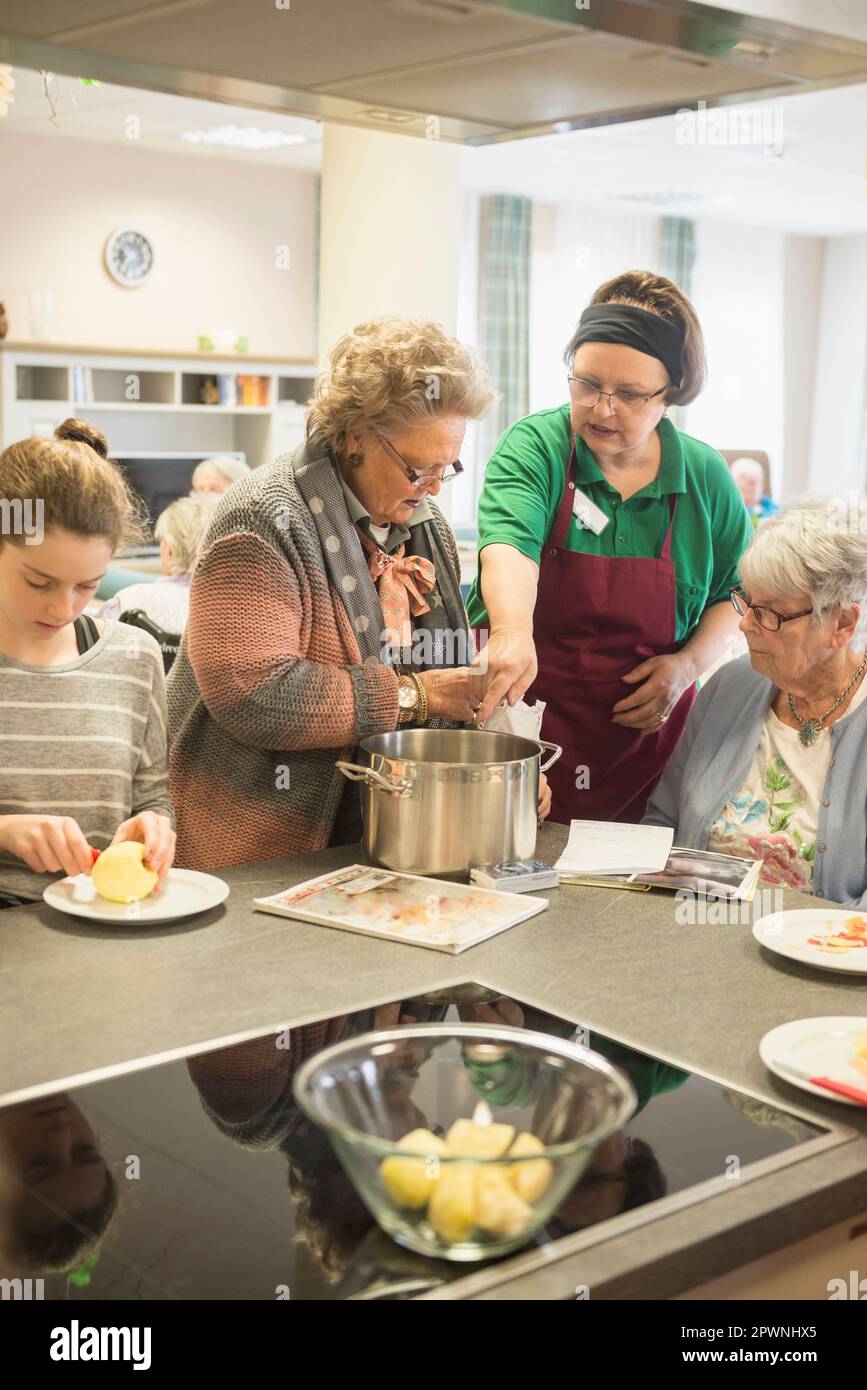Nurse with senior women and girl preparing food at rest home Stock Photo