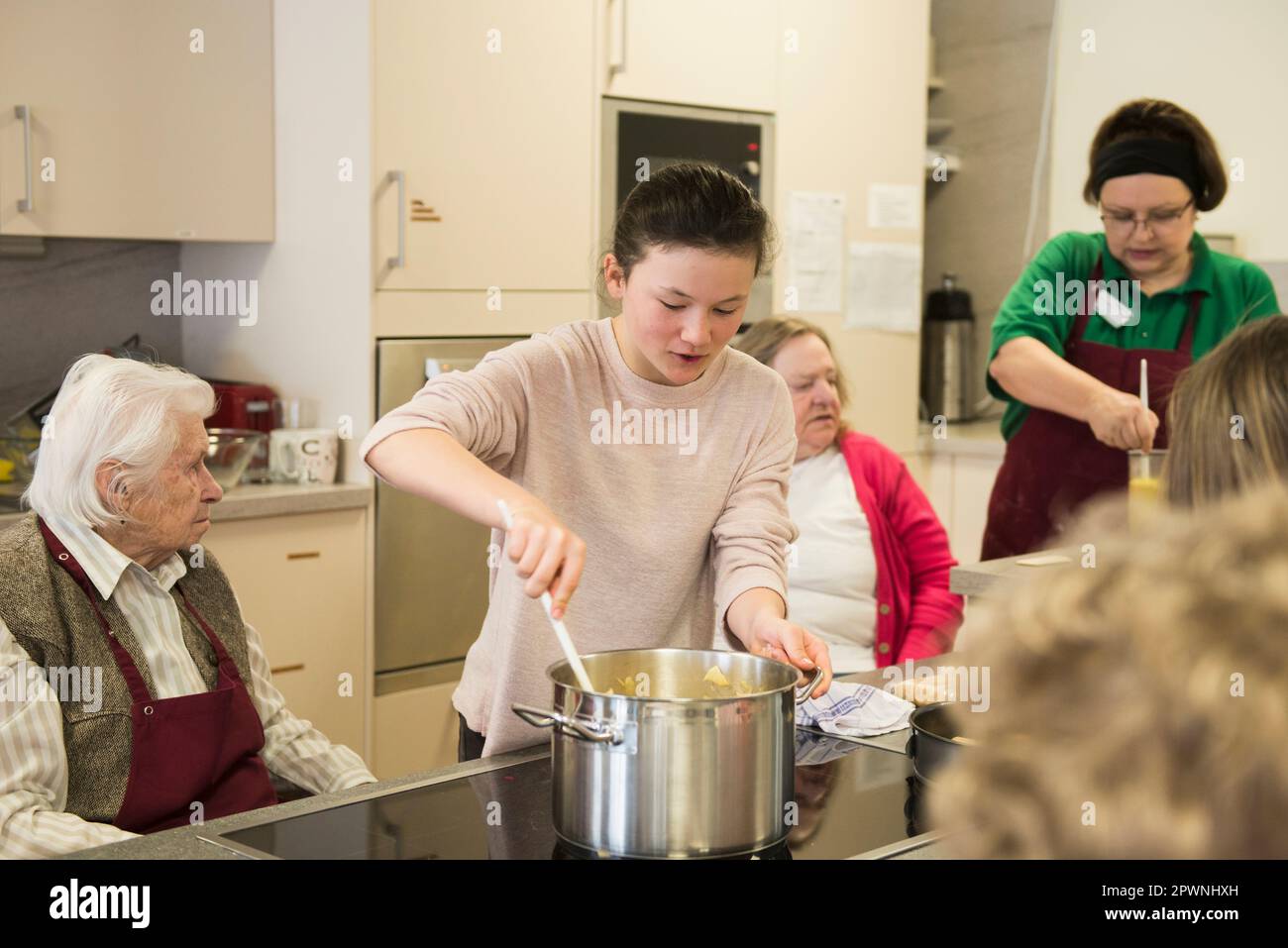 Nurse with senior women and girls preparing food at rest home Stock Photo