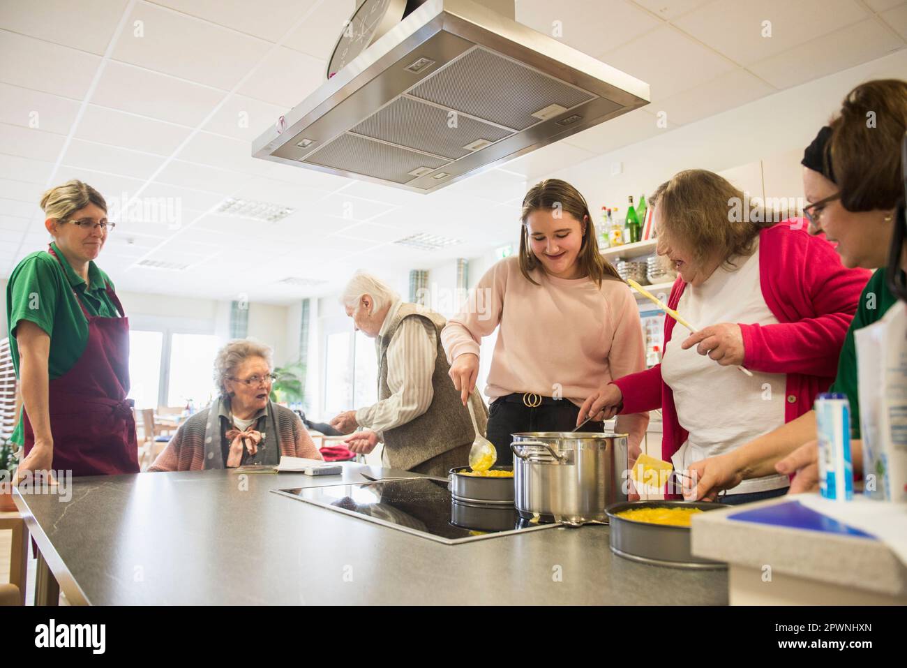 Nurse with senior women and girls preparing food at rest home Stock Photo