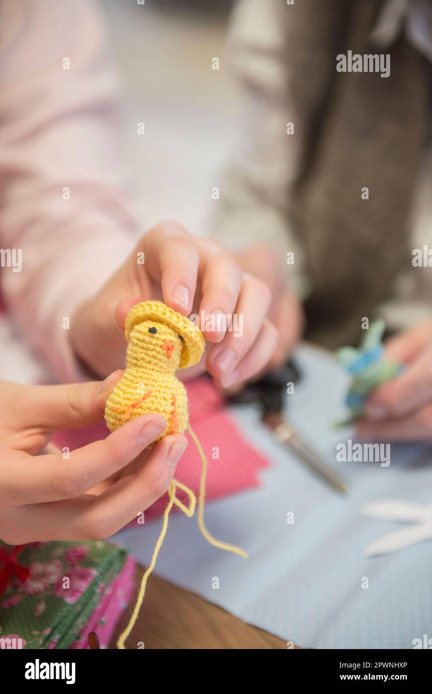 Senior woman with girl holding handmade crochet chick at rest home Stock Photo