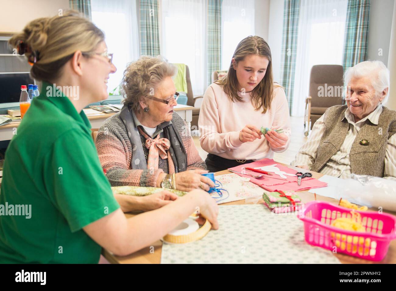 Senior women with girl and nurse doing craft activity at rest home Stock Photo