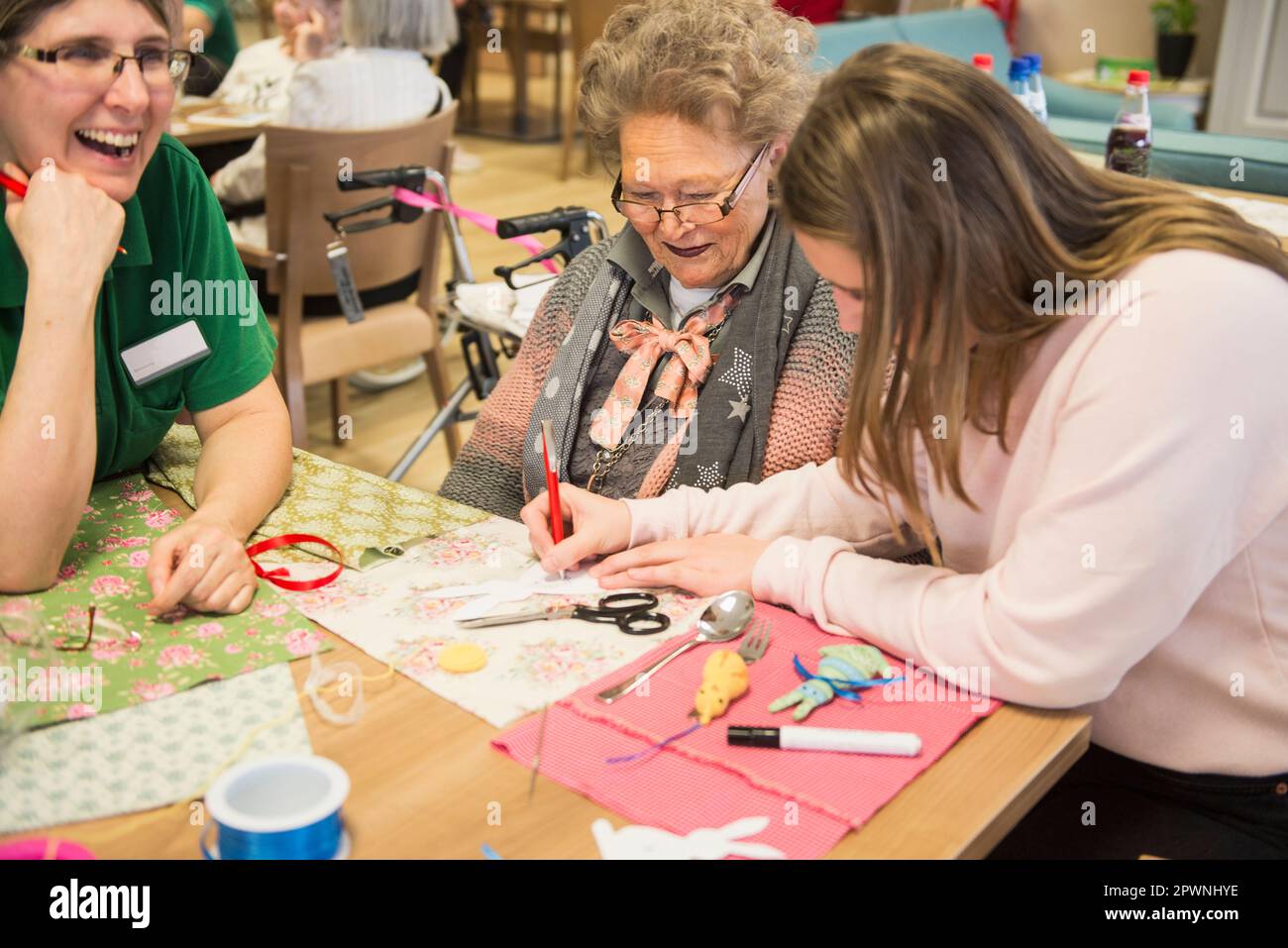 Senior women with girl and nurse doing craft activity at rest home Stock Photo