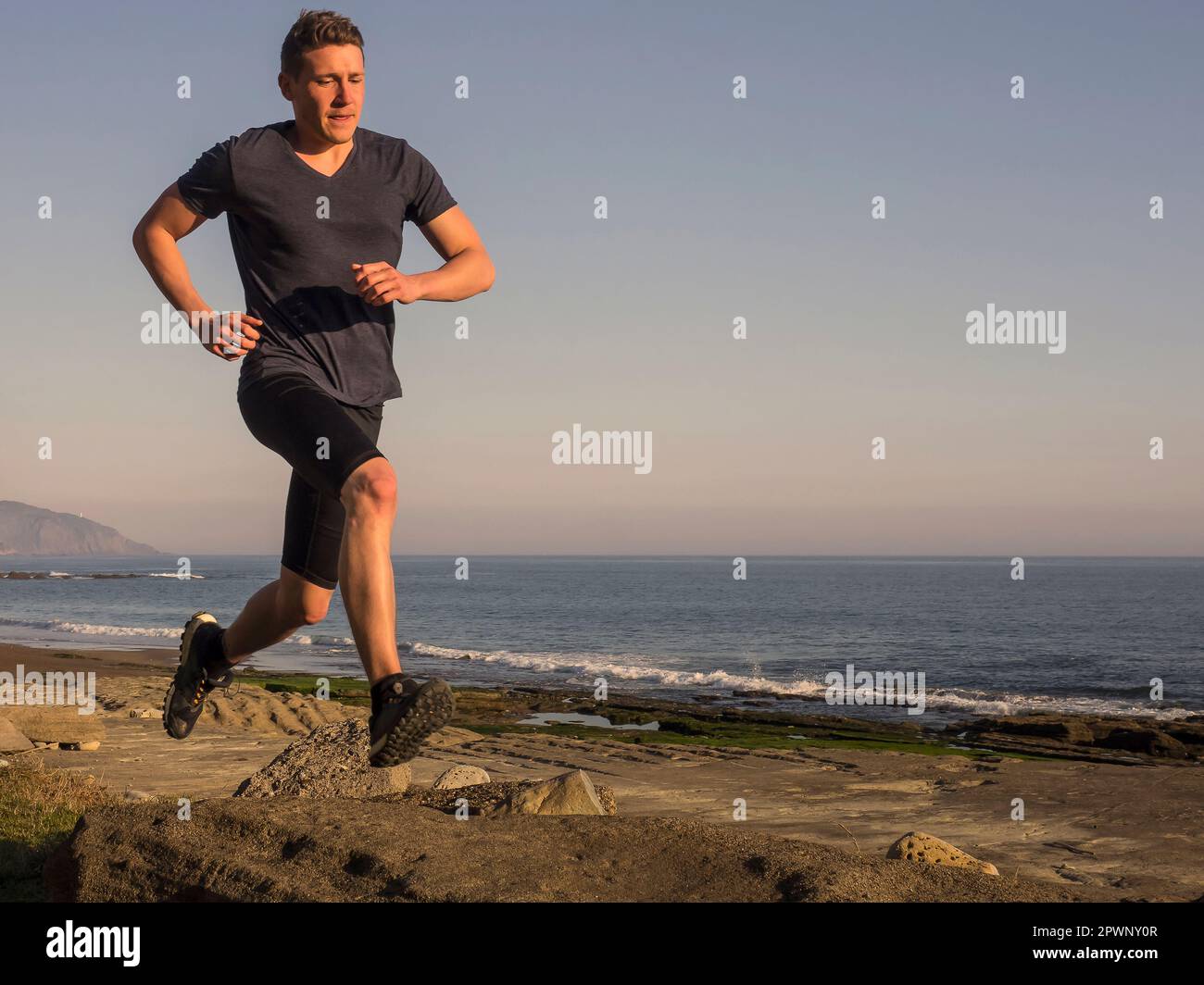 Man trail running on the coast of Azkorri beach Stock Photo