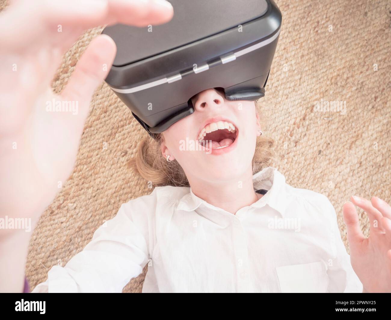 Girl using virtual reality headset while lying on floor Stock Photo