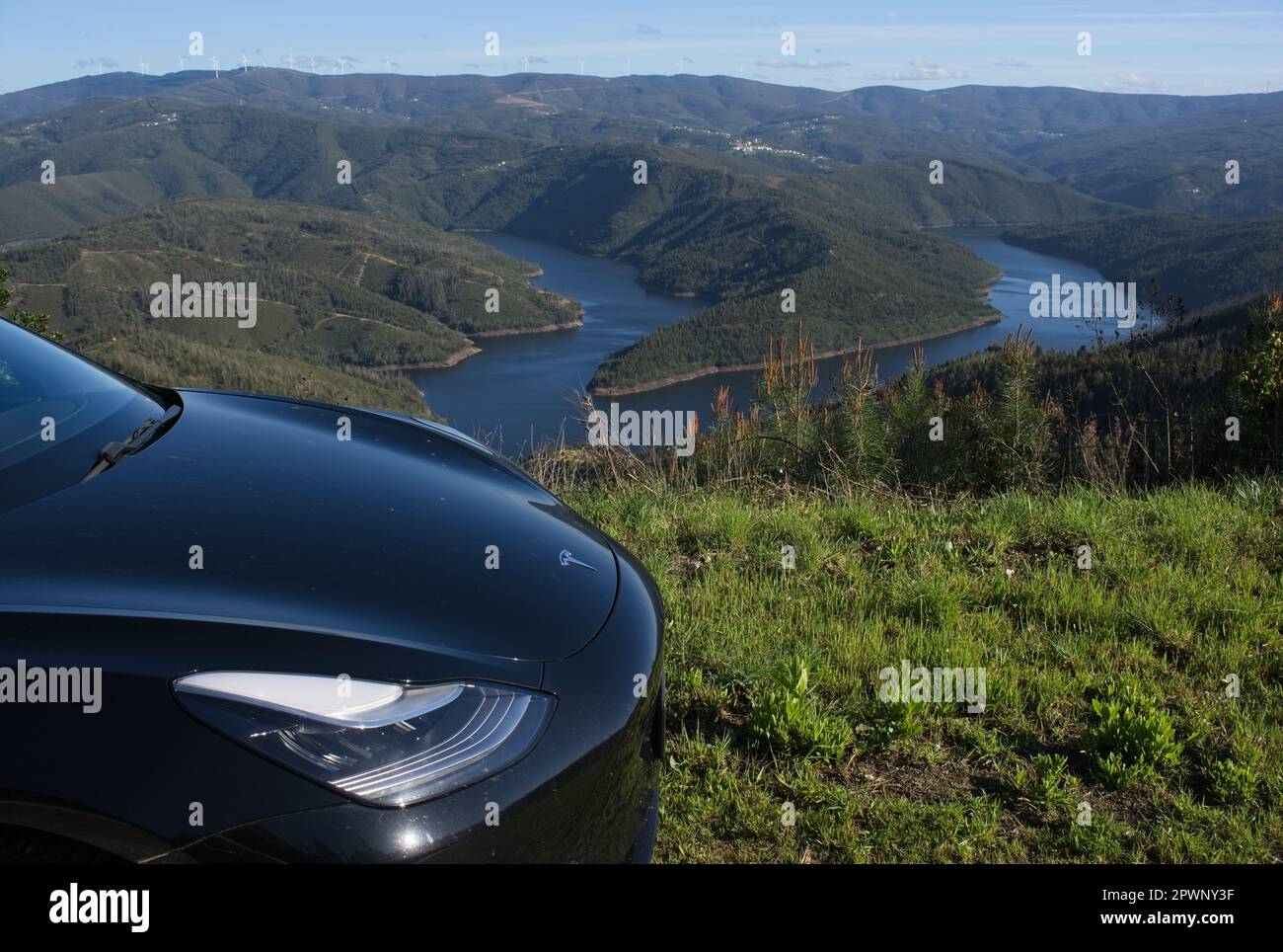 Fundao, Portugal - March 24, 2023: Beautiful scenery from the Miradouro de Sarnadela. Static shot of a solid black Tesla Model 3. Sunny spring day Sel Stock Photo