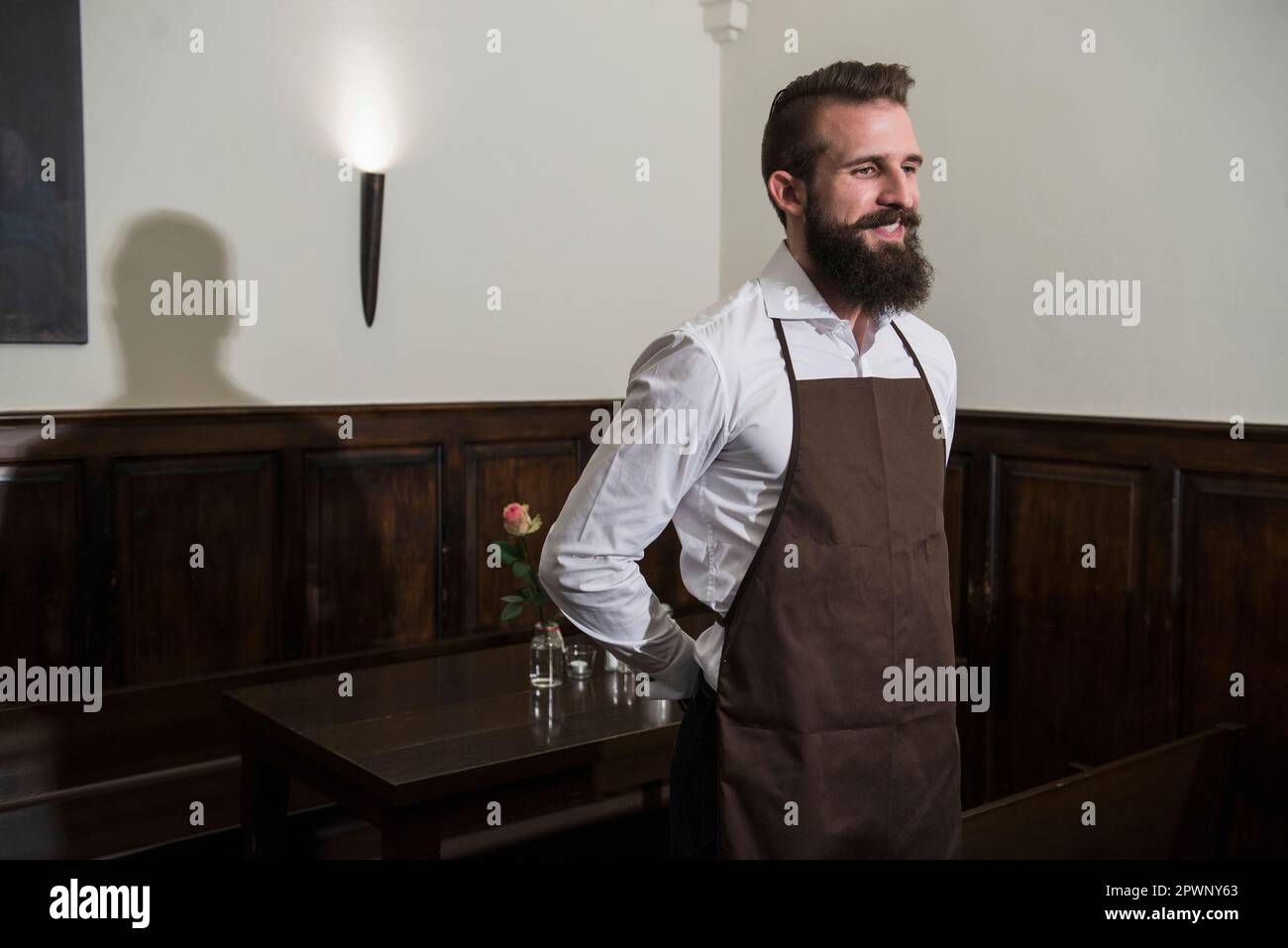 Contemplative smiling manager standing by table at restaurant Stock Photo