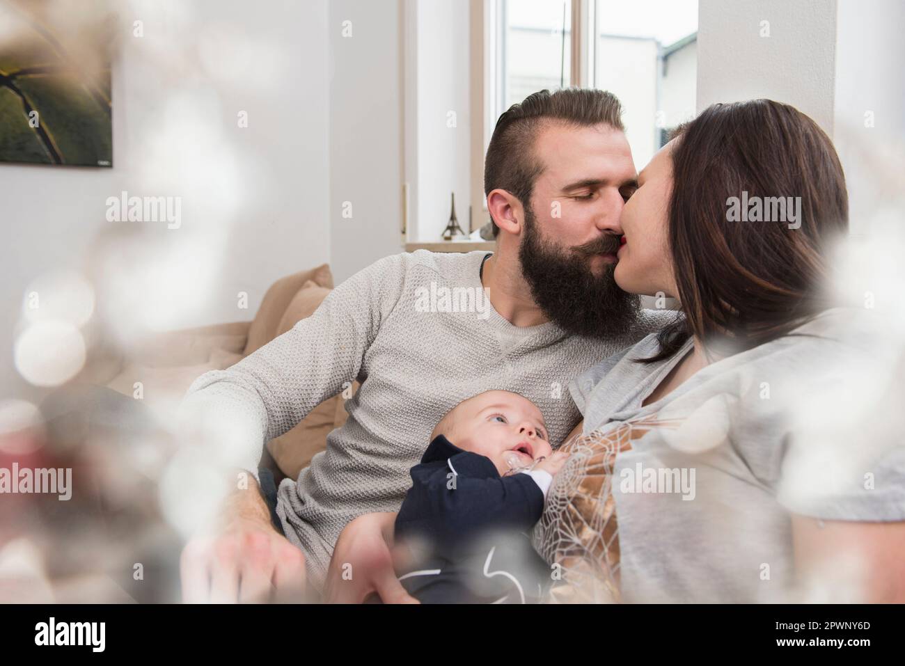 Couples kissing with baby on sofa Stock Photo