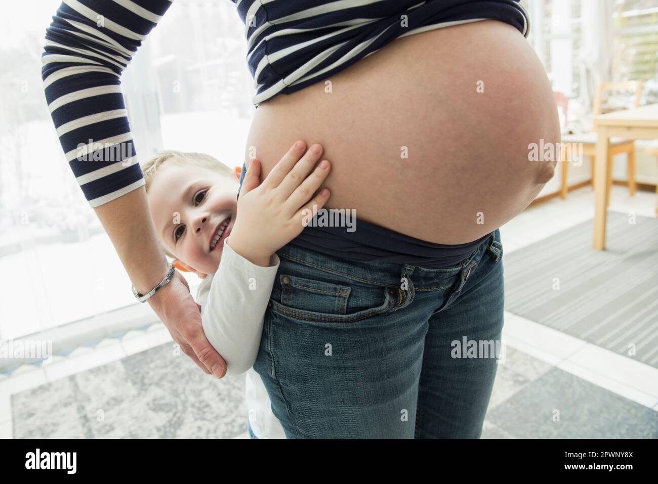Son hiding behind pregnant mother's belly Stock Photo Alamy