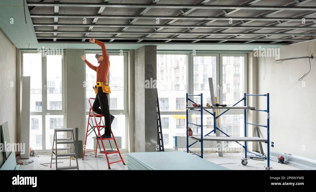 Builder fastens profile using cordless screwdriver Stock Photo