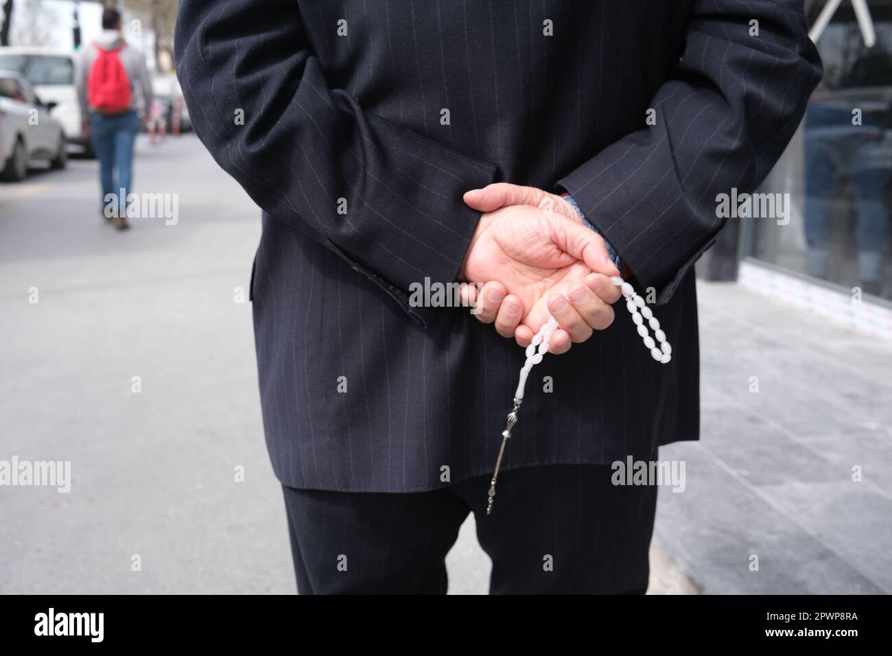 A man holding a rosary behind his back Stock Photo