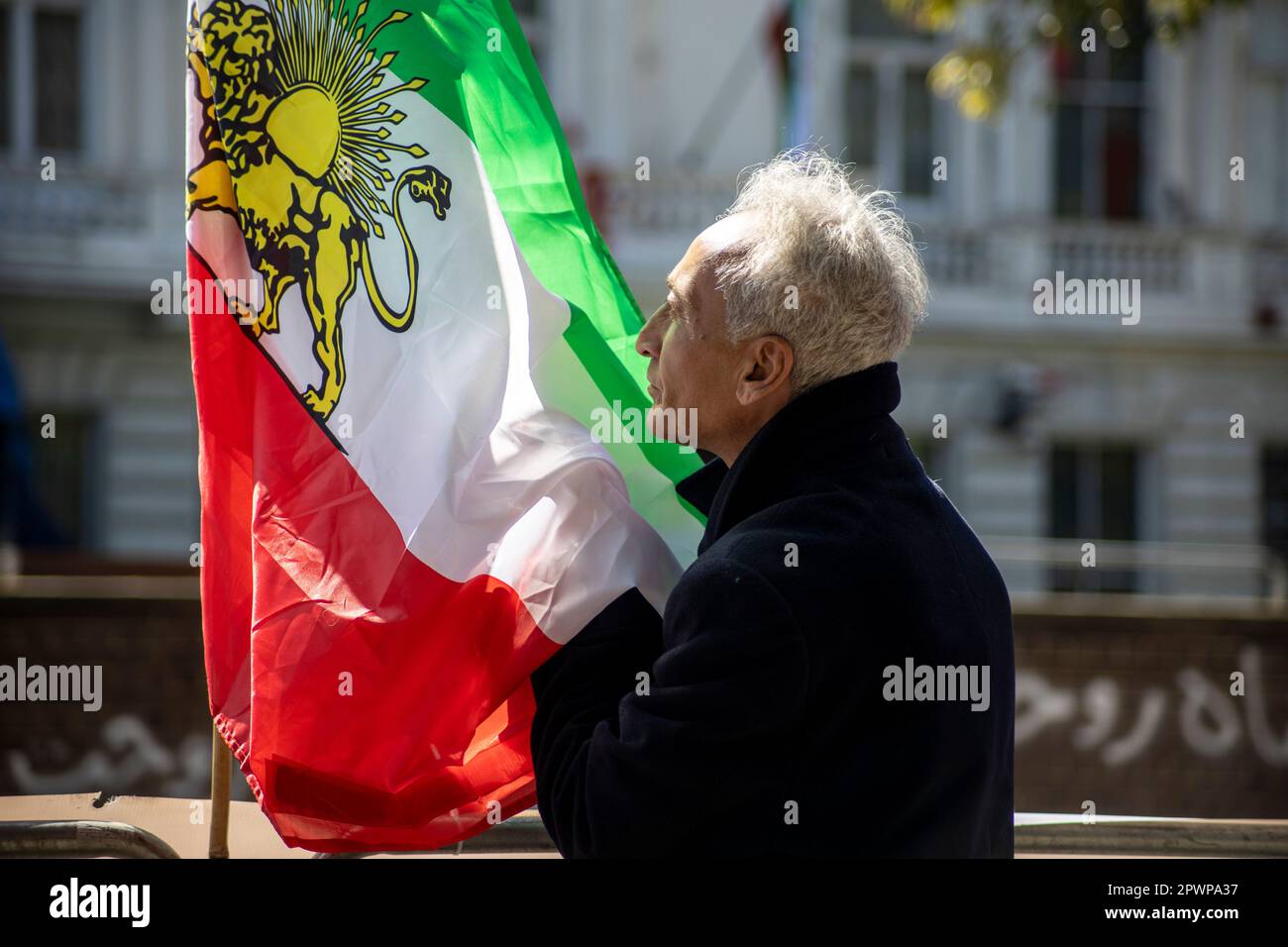 A patriot pays tribute to the 'Shir-o-Khorshid' (Lion and Sun) flag of Iran during an anti-regime protest in front of the Islamic Republic of Iran's e Stock Photo