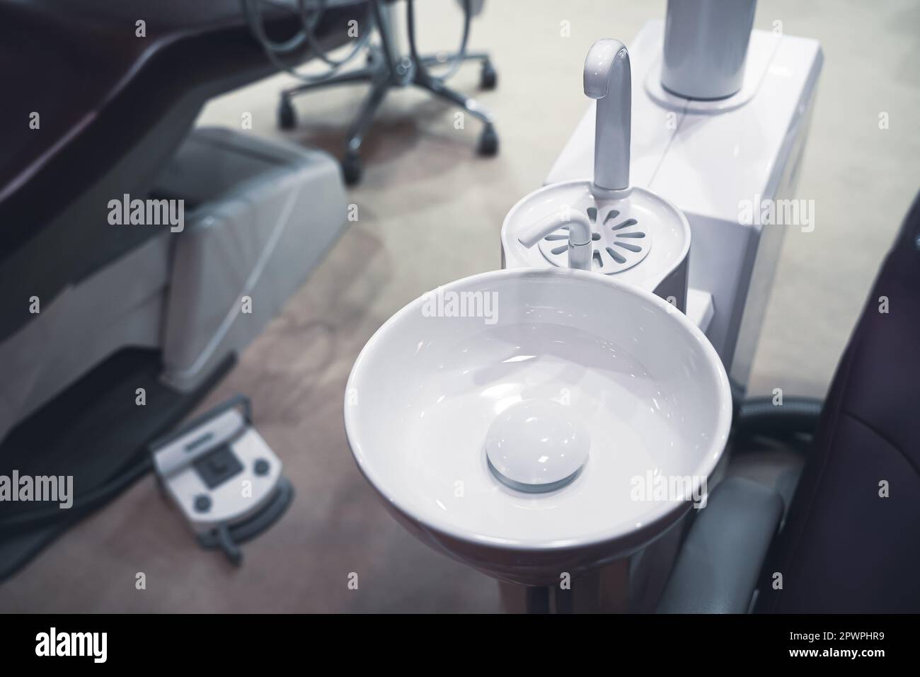 closeup top view of clear dental white ceramic spit sink near chair in